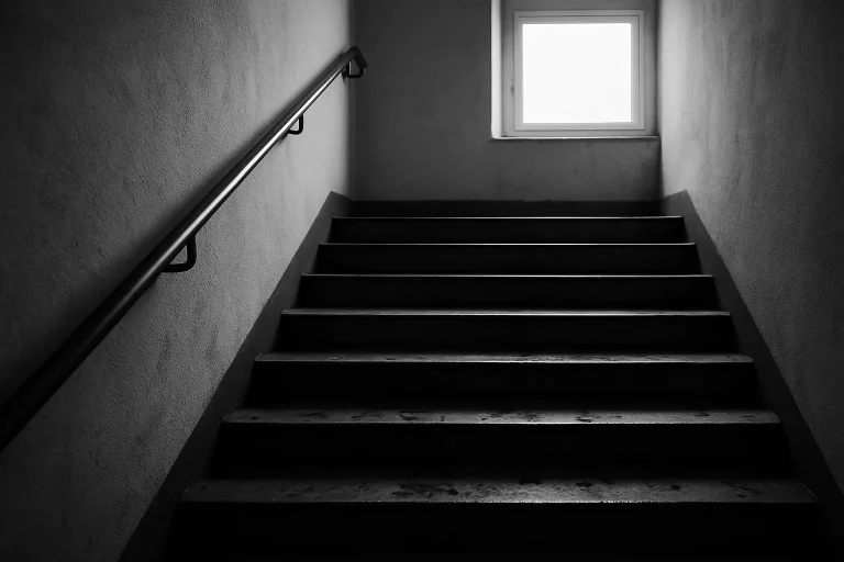 Cage d'escalier avec souillures visibles sur les marches, éclairage naturel.